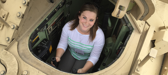 Woman smiles while sitting inside a Bradley Fighting Vehicle.