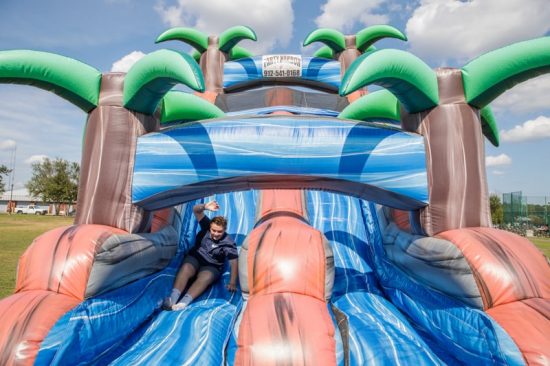 person speeding down an inflatable slide in an image of an oasis